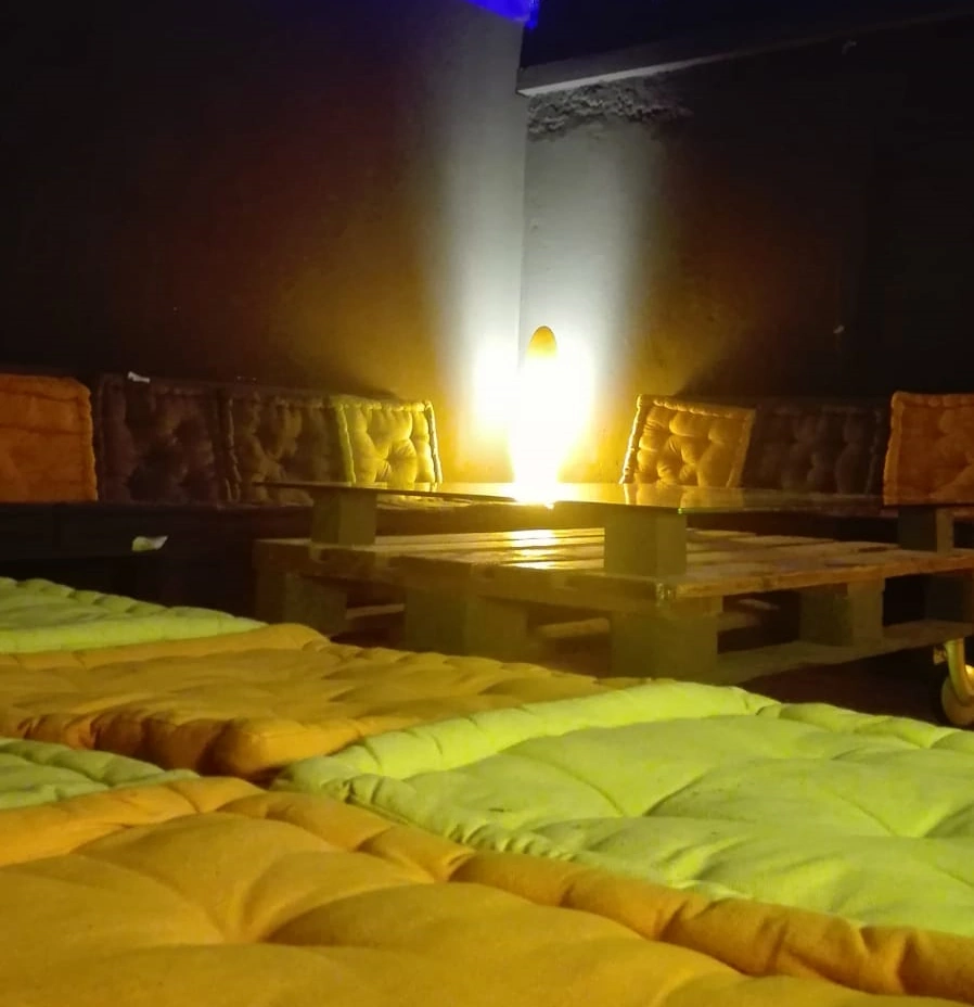 Tavoli in pallet e salottini modulari nella sala per team building aziendali a Milano, ideali per meeting informali e pause caffè.